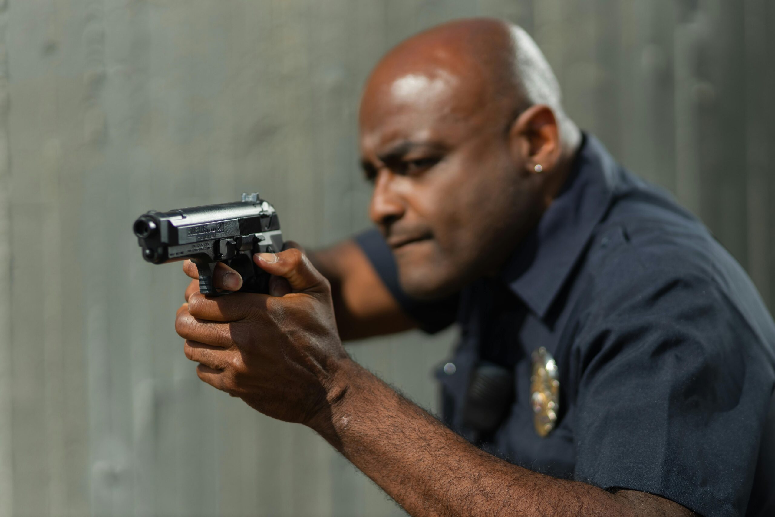 A close-up of a police officer aiming a handgun, demonstrating focus and precision outdoors.