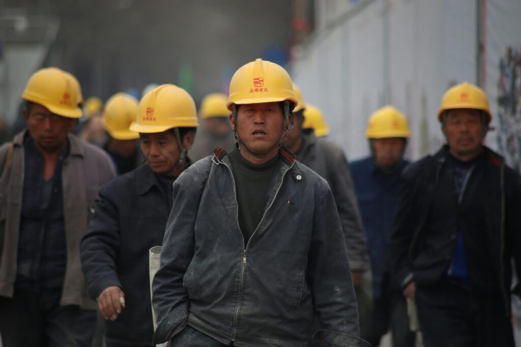 work-chinese-industrial-professional-33266 Construction workers in hard hats walking at a site, highlighting teamwork and safety.